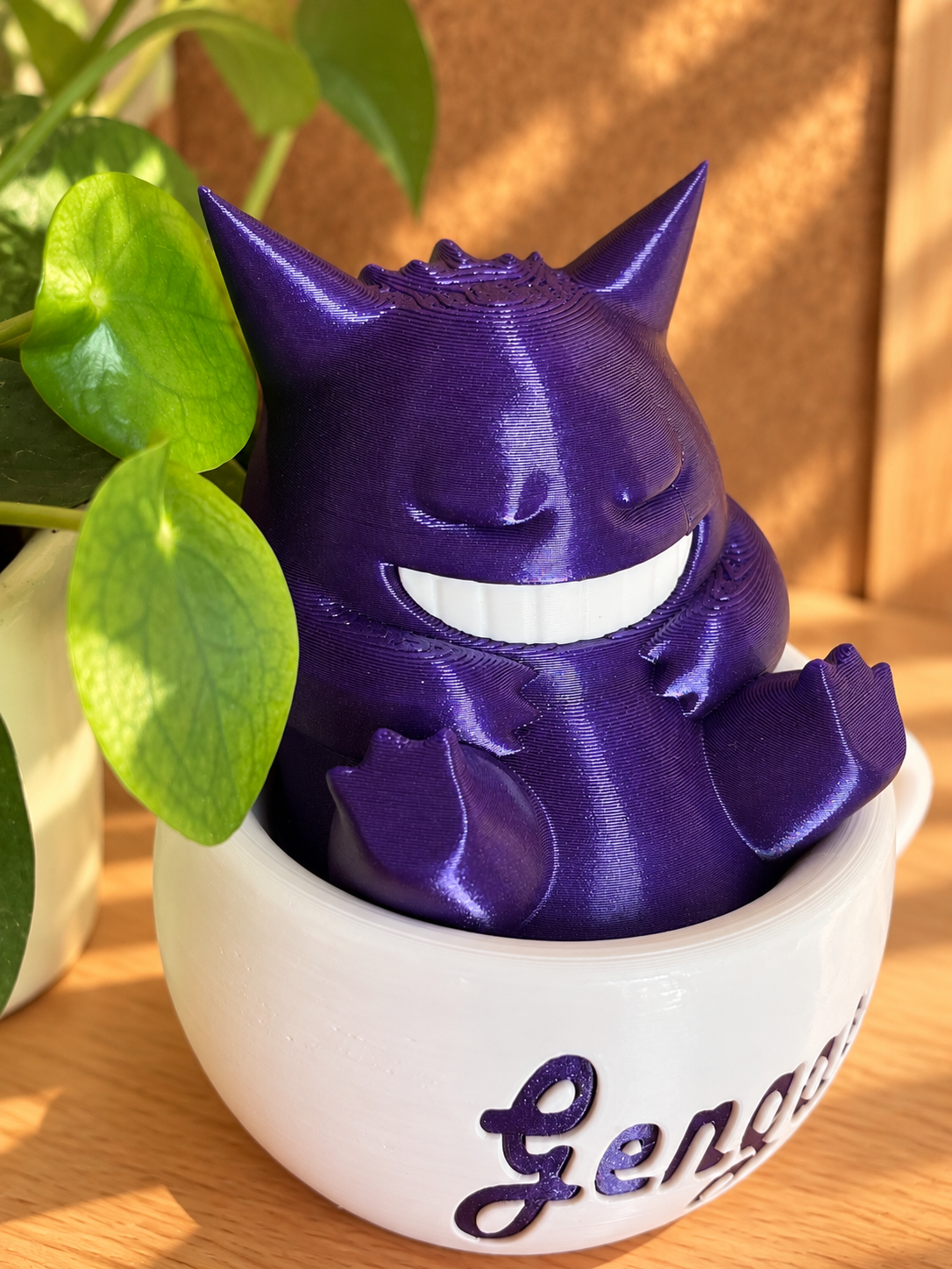 Detalle del acabado brillante de la figura morada de Gengar y la taza decorativa blanca